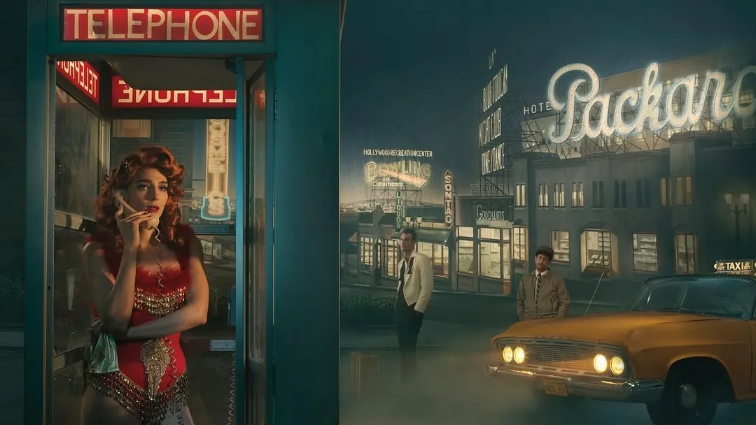 A woman waits in a lit phone booth while a painted night-street backdrop, a parked car and two men stand behind her