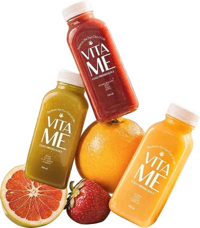 Three cold-pressed juice bottles stacked with an orange, a grapefruit half and a strawberry