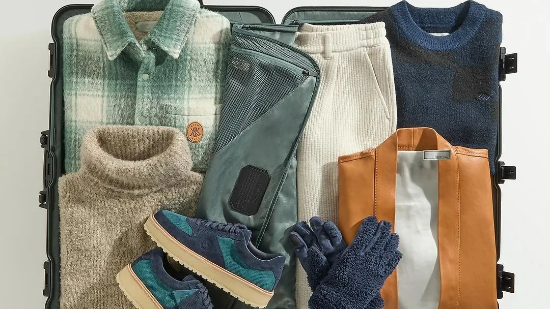 An open hard case packed with a season of knitwear, boots, gloves and bags, shot flat from above